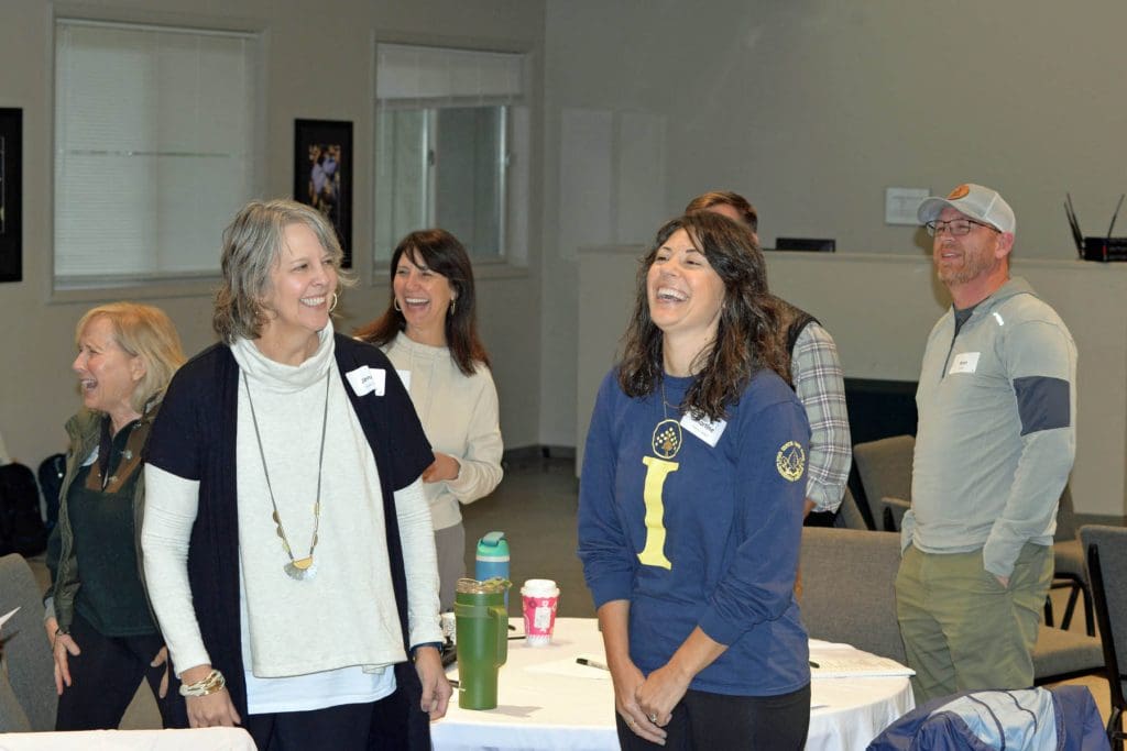 Group of nonprofit CEOs standing and laughing during an ice breaker activity.